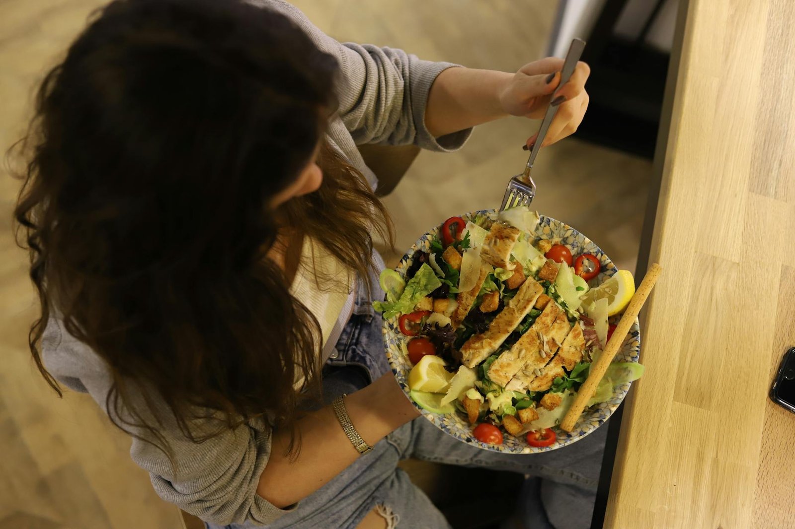 overhead shot of a woman eating a salad, healthy eating habits.